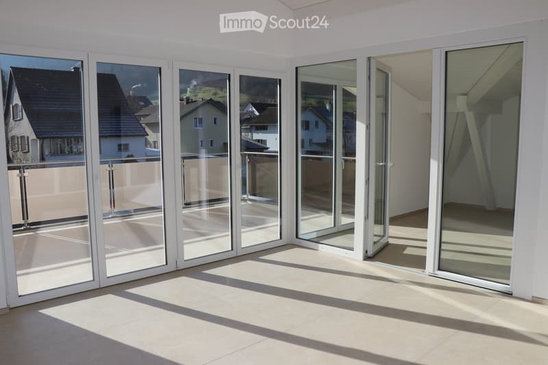 sliding glass doors leading to balcony, large windows, white walls, tiled floor, balcony with railings