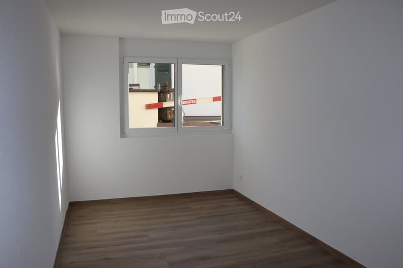 empty room with a window, wooden floor, and white walls