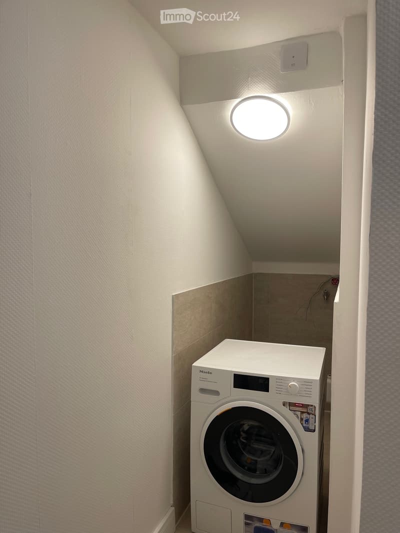 Laundry room with built-in washing machine, tile wall, ceiling light
