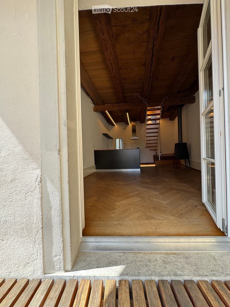 Corridor / Hallway. Raised ground floor entrance leading into a modern, wooden-floored hallway with exposed wooden beams and a staircase visible in the background.