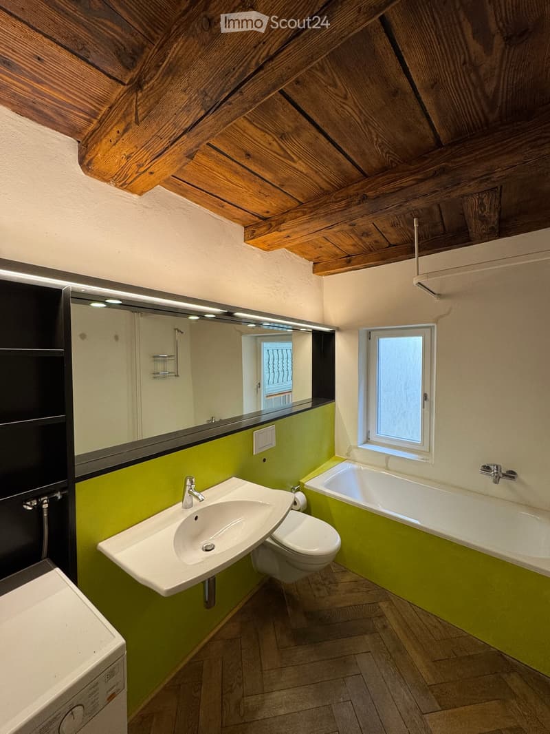 Bathroom. Bathroom with a wooden ceiling, green lower walls, white upper walls, a sink, toilet, bathtub, and a large mirror with LED lighting.