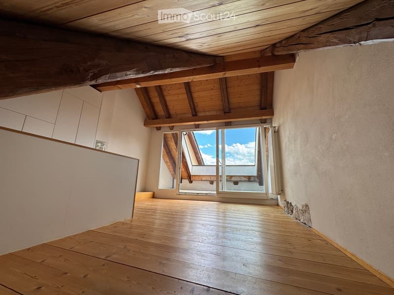 Unfurnished Room. Empty room with wooden floor, exposed wooden ceiling beams, and large windows offering a view of the sky.