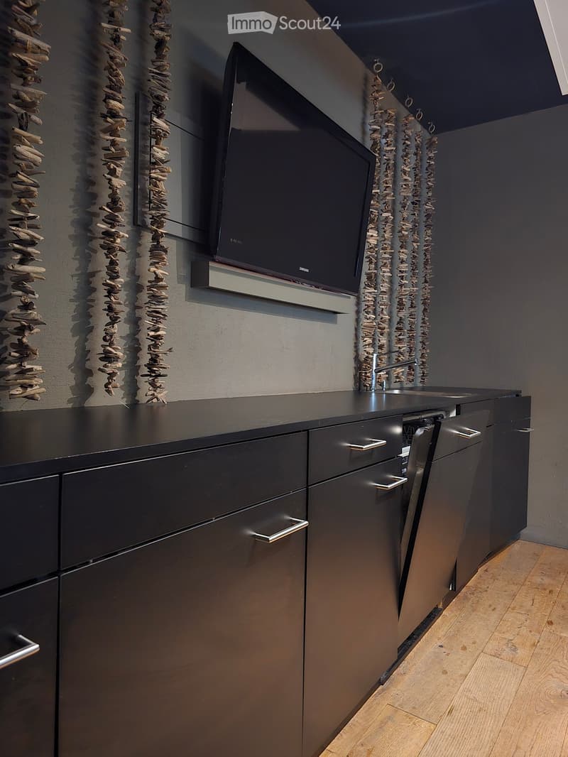 modern kitchen, wall-mounted Samsung TV, black cabinets, dishwasher, faucet, wooden floor