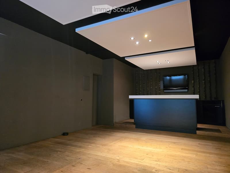 empty room, white ceiling with embedded lights, blue bar counter, tv mounted on the wall, wooden floor