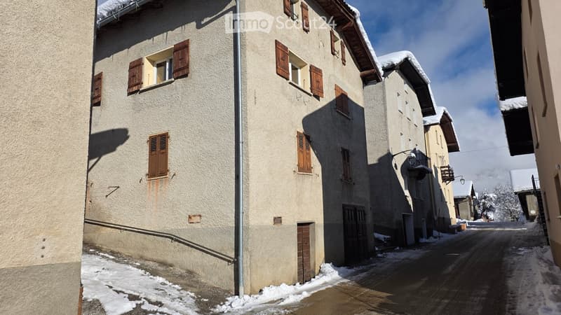 multi-story building, wooden shutters, snow on the roof, wooden garage doors, empty street