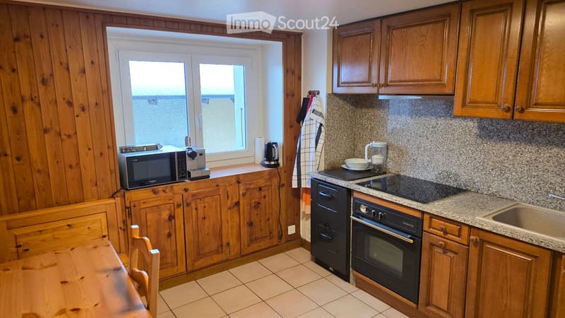 wooden cabinets, granite countertop, sink, black oven, black fridge, microwave on window sill, wooden dining table