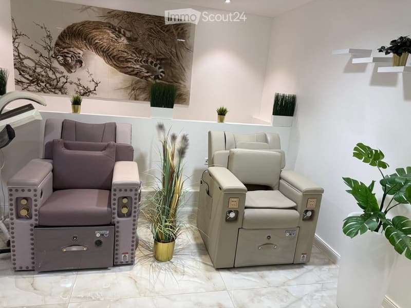 Two high-end salon chairs, a large wall painting of a tiger, decorative plants, elegant white and marble flooring.