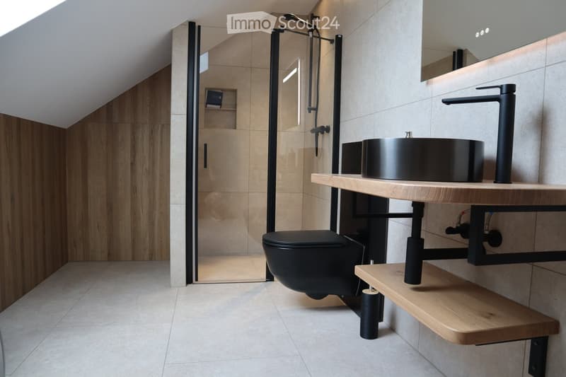 modern design bathroom with black fixtures, wooden wall cladding, white tiled floor, separate shower area, wooden vanity with black metal support, mirror above vanity