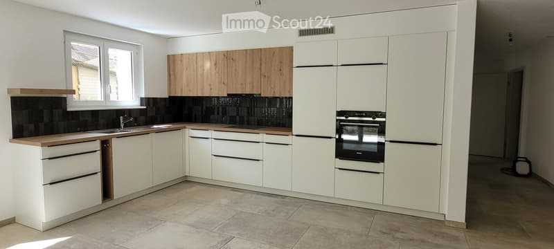 Modern kitchen with white cabinets, wooden countertops, black tiled backsplash, and stainless steel appliances.