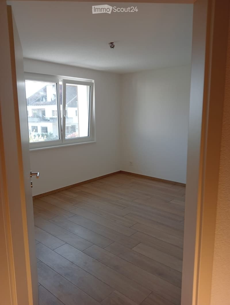 Empty room with white walls, wooden floor, and a window. No furniture or equipment.