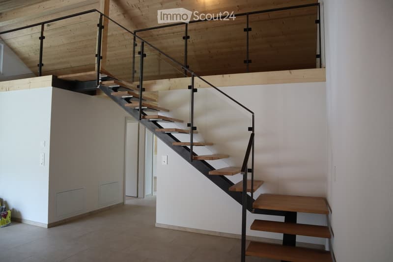 Contemporary staircase with glass railings and wooden steps, elevated ground floor, white walls, tiled floor.