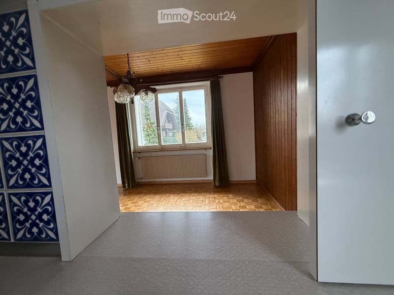 empty room, wooden floor, window with white frame, radiator, decorative wall tiles, chandelier