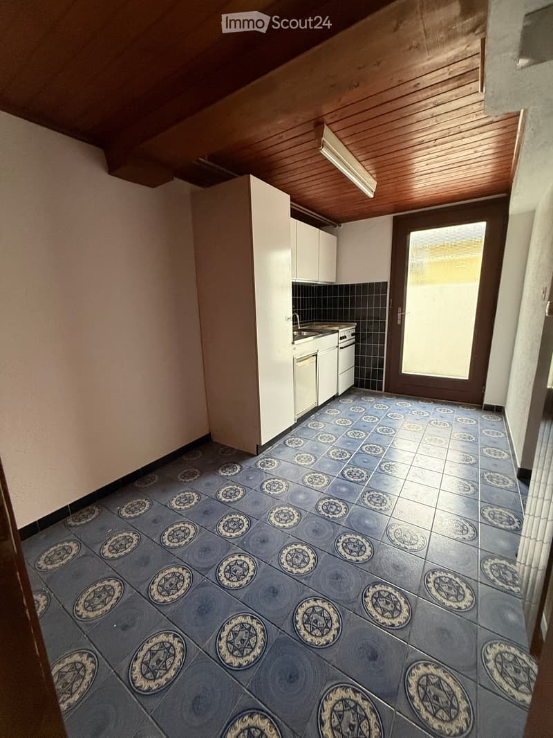 empty kitchen with blue and white tile, wooden ceiling, white cabinets, sink, gas stove