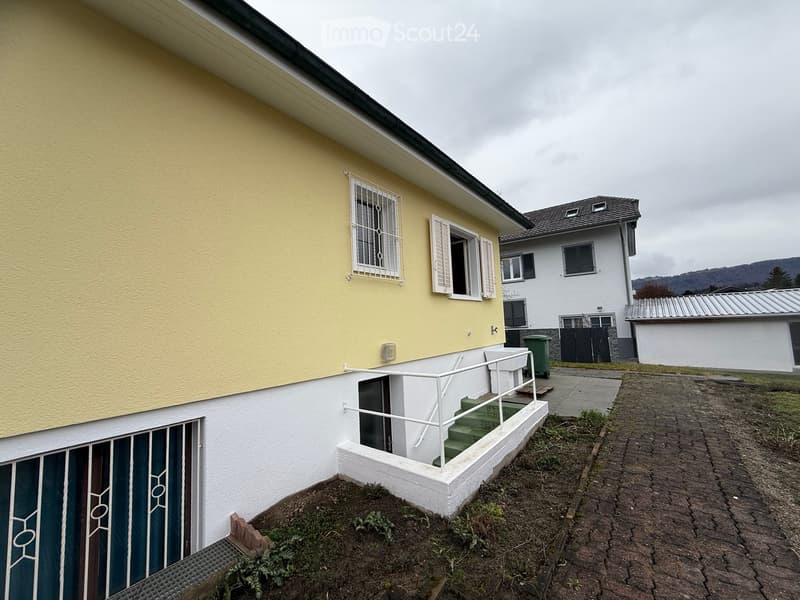 Two story house, yellow and white painted exterior, paved driveway