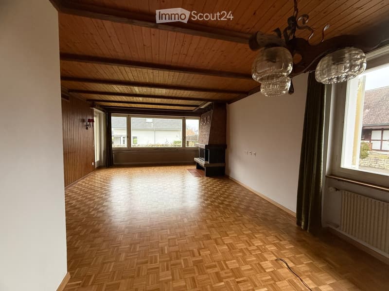 Wooden parquet floor, fireplace, wall-mounted lamps, windows, radiator, wooden ceiling beams