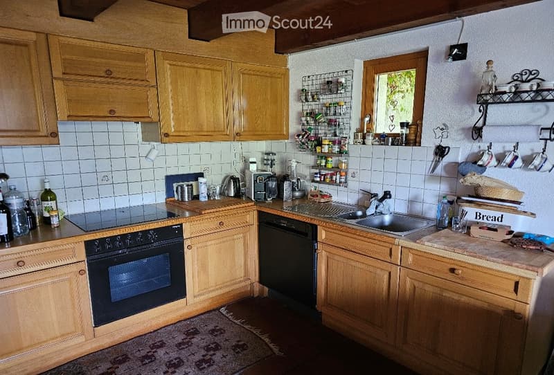 light oak cabinets, island with sink, gas stove, dishwasher, refrigerator, wooden floor