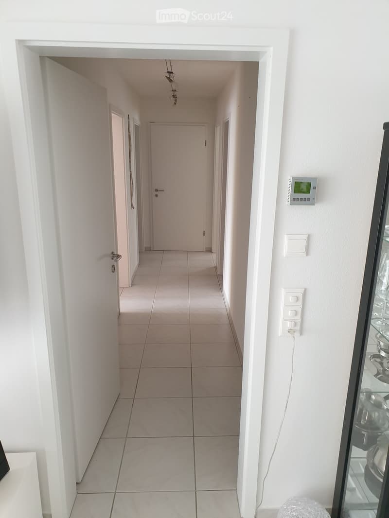 hallway, white tile flooring, white doors, white walls, electrical outlet