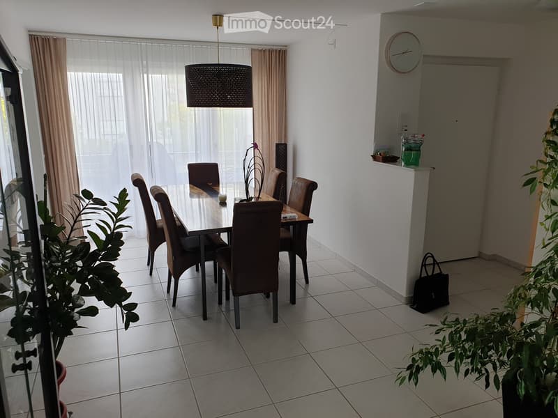 Dining room with dining table, six chairs, lamp, plants, tiled floor, curtained window, clock on wall, shelf, handbag