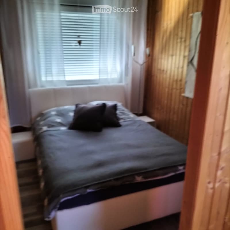 white bed with pillows, white bedsheet, wooden wall with horizontal lines, white curtains on window
