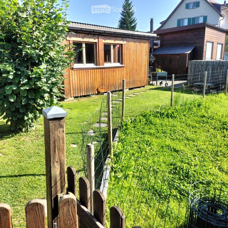 Garden with wooden fence, grass, plant, and garden tool holder.