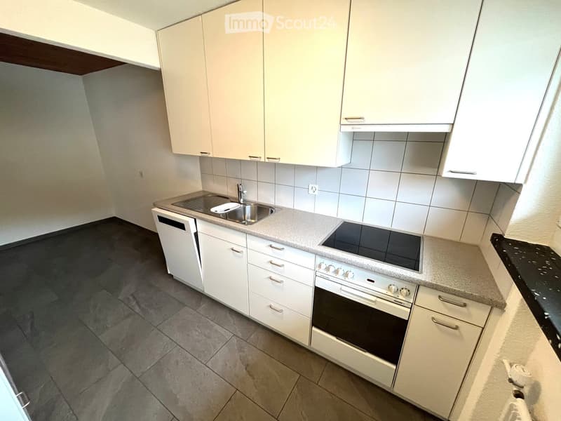 Modern kitchen with white cabinets, tiled walls, a sink with faucet, electric stove, and a dishwasher under the countertop