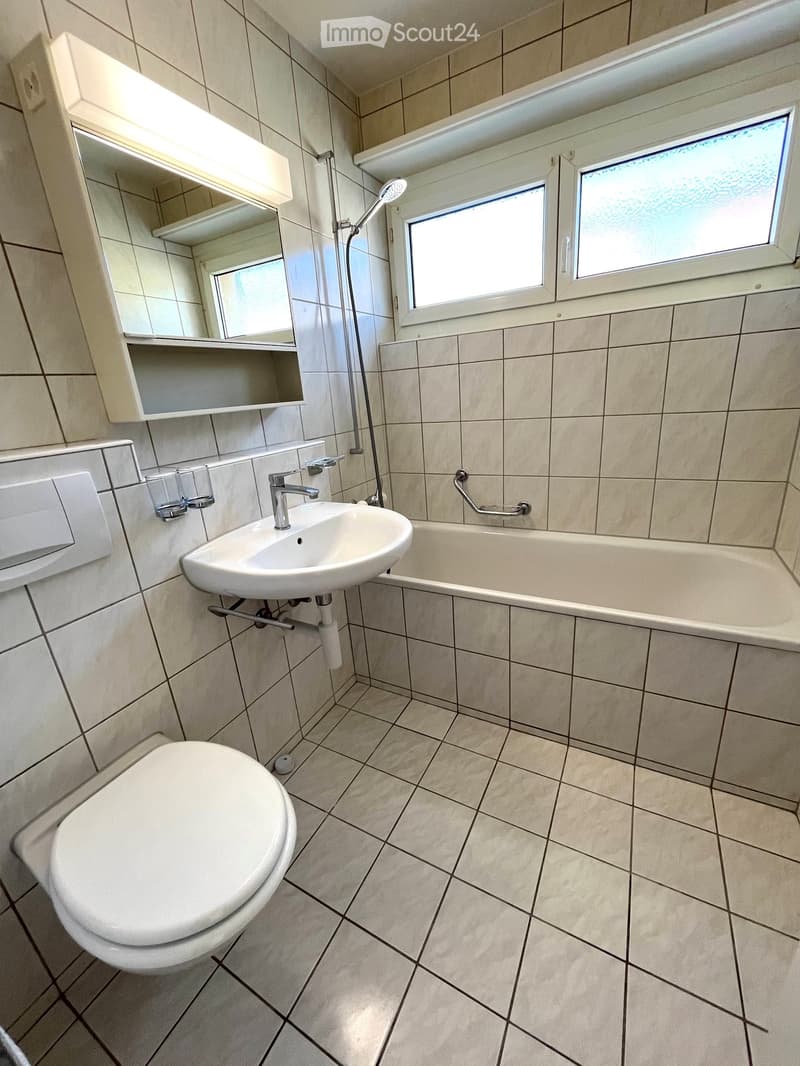 bathroom with white tiles, shower, bathtub, sink, toilet, and mirror with light