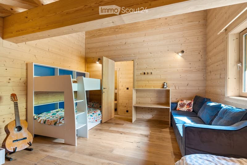 Cozy wooden cabin interior with bunk beds, shelving, sofa, and guitar
