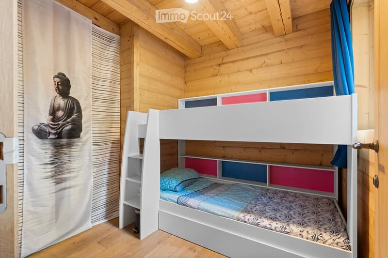 Wooden cabin-style bedroom with bunk beds, colorful storage drawers, and a large Buddha statue on the wall.
