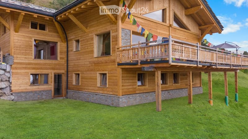 two-story wooden chalet with balcony on the upper floor, stone base