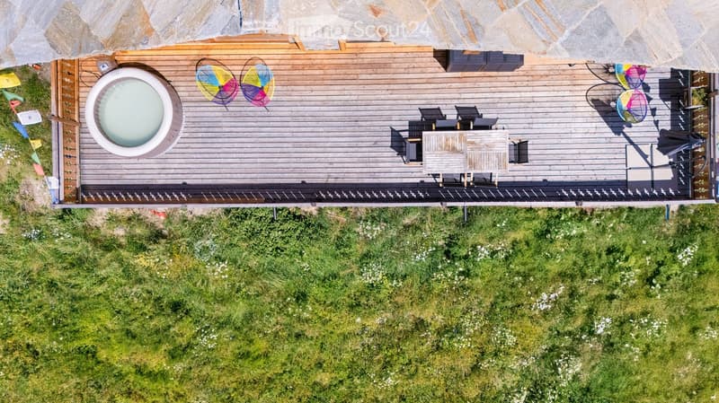 Wooden deck with colorful butterfly decorations, outdoor seating area, surrounded by lush green vegetation