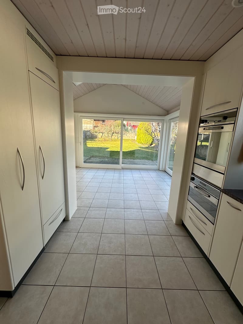 Kitchen with large windows, tiled floor, oven, large wooden cupboards, modern design