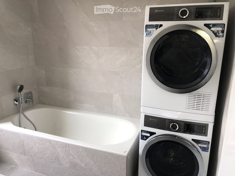 Bathroom with bathtub, shower, and stacked washer and dryer.