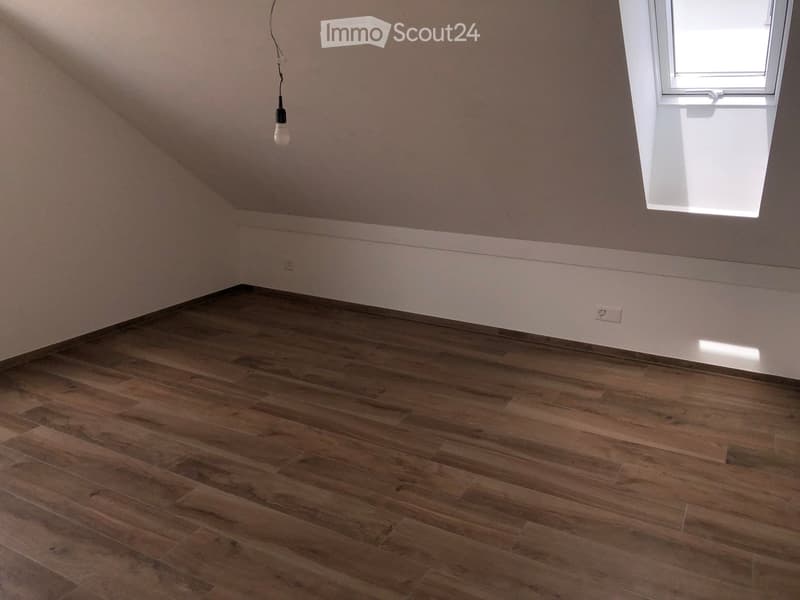 empty room, wooden floor, white walls, slanted ceiling, attic window, power outlet
