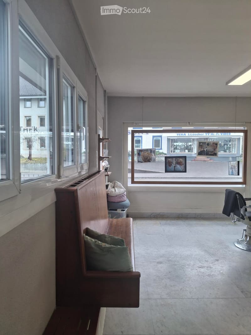 An empty room with wooden bench, window with view to the outside, and a shelf