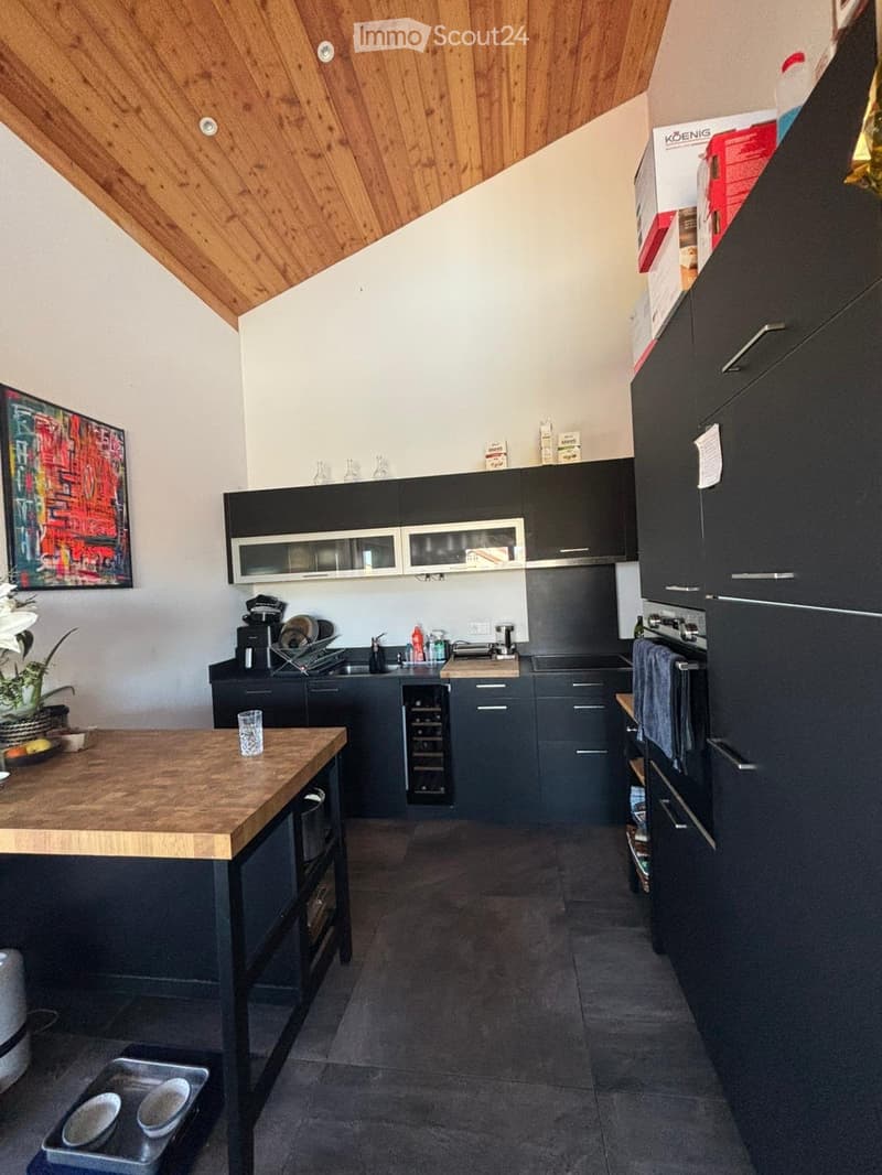 modern kitchen with wooden ceiling, black cabinets, wooden countertop, island, wine cooler, oven, sink, coffee machine, flowers, painting