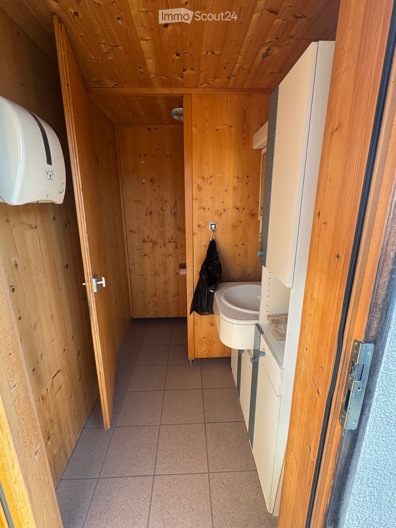 small bathroom, wooden walls, tiled floor, sink, towel rack, soap dispenser