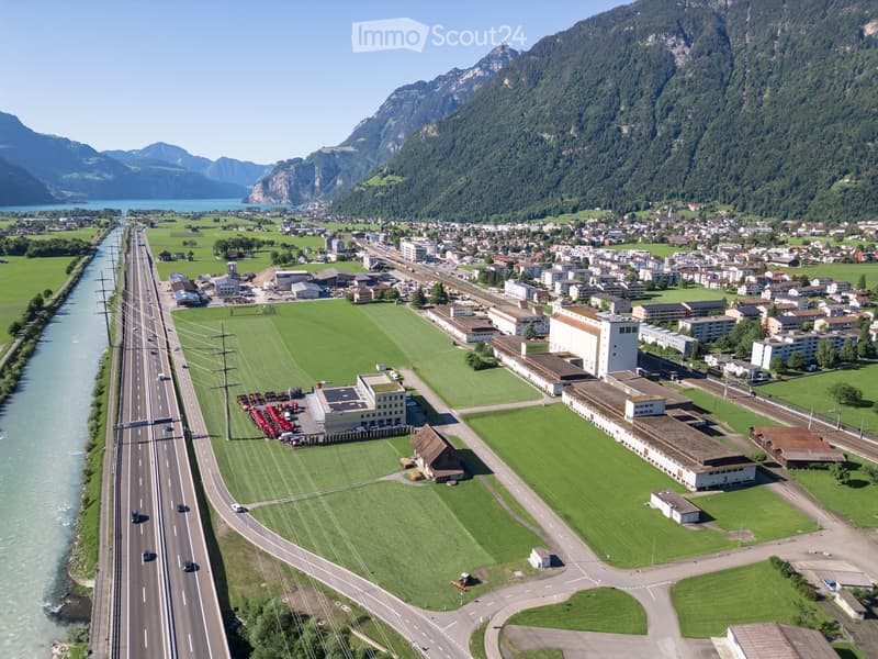 Countryside scenery with highway, houses, green fields, river, mountains, large building with solar panels