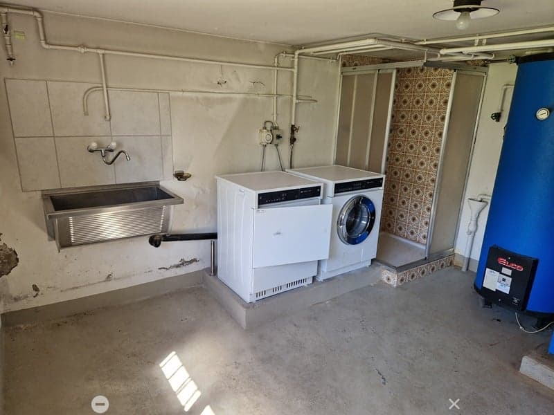 concrete floor, white washing machine, white dryer, sink, tiled wall