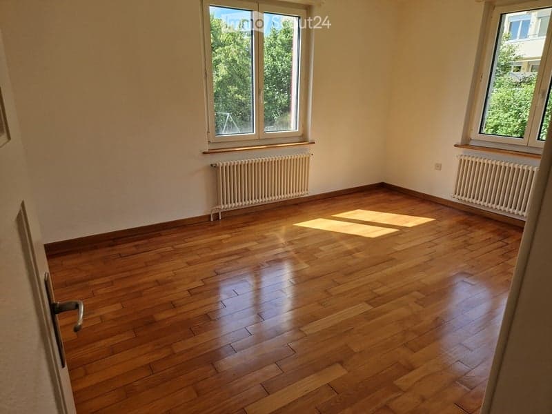 hardwood floor, white walls, two windows, two white radiators, no furniture