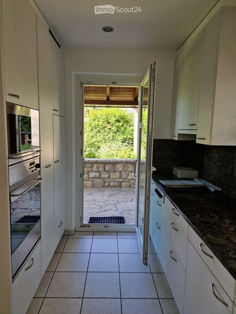 modern kitchen with white cabinetry, stainless steel appliances, granite countertops, open door leading to outdoor patio, tiled floor