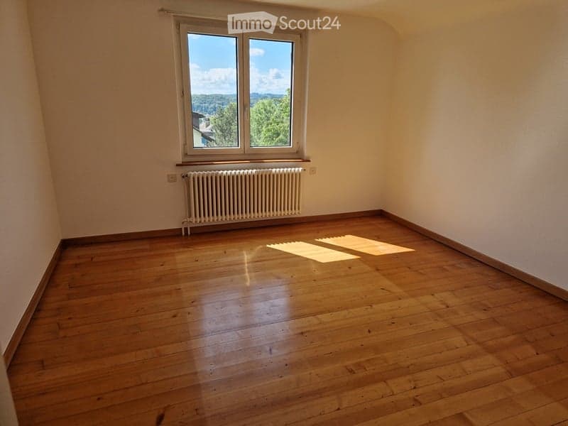 wooden floor, white walls, radiator, window with outdoor view