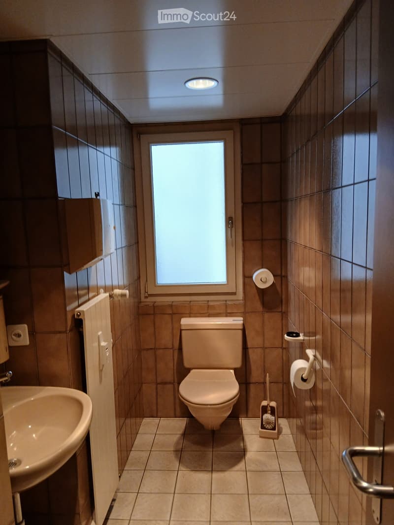 small bathroom, white sink, brown tiles, small window, white toilet, towel holder