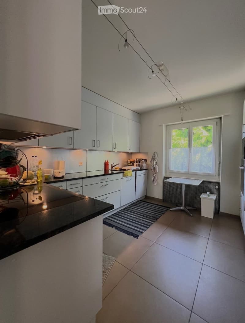 modern white kitchen with wooden countertops and tiles, built-in appliances, white cabinets, open window with view