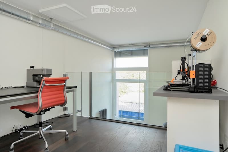 modern office space with white walls, wooden floor, a desk, office chair, and printing machine, with a glass window overlooking a building
