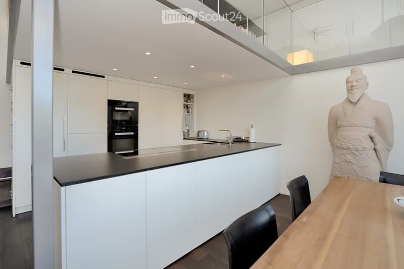 modern kitchen with island, oven, large sink, dining table, black chairs, statue, white cabinets
