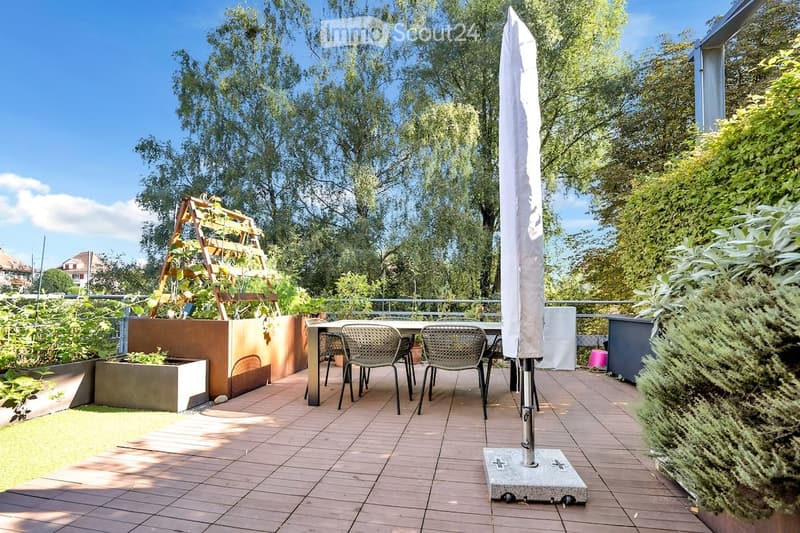 Wooden deck, dining table and chairs, plants, umbrella, metal railing, and a balcony with a view