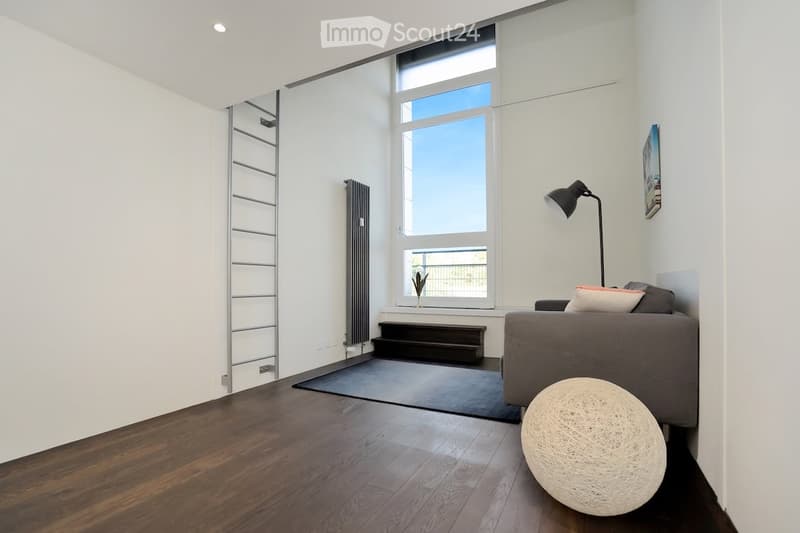 Modern living room with large window, gray couch, round ball lamp, black rug, ladder, small picture frame on wall