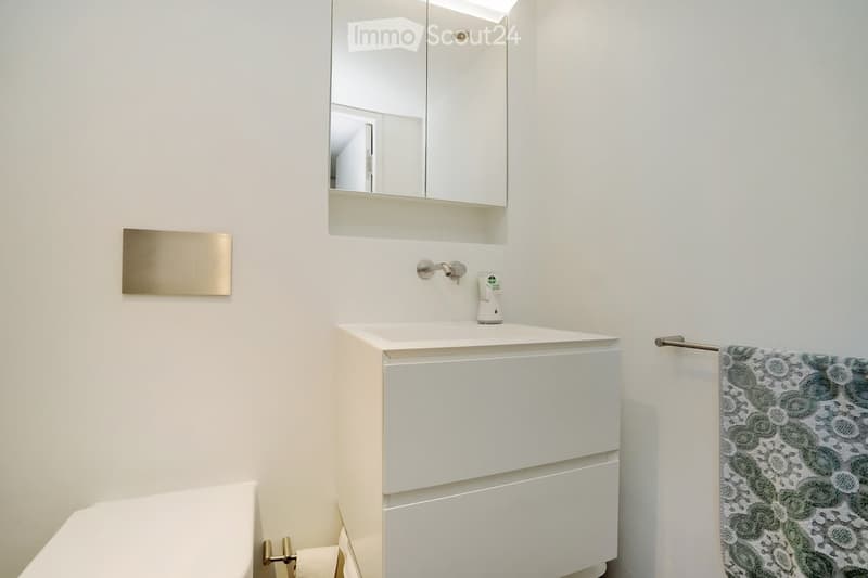 A small modern bathroom with white walls, modern fixtures, and a vanity with sink, two drawers, and towel rack.