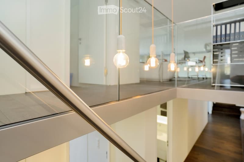 Interior with glass railing, wooden floor, hanging light bulbs