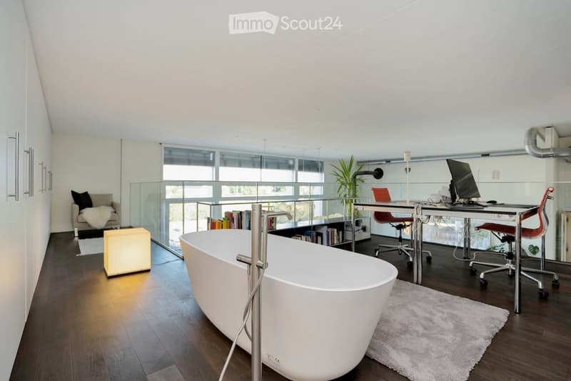 large bathtub, glass wall with terrace access, wooden floor, white walls, modern furniture, desk with computers, office chairs
